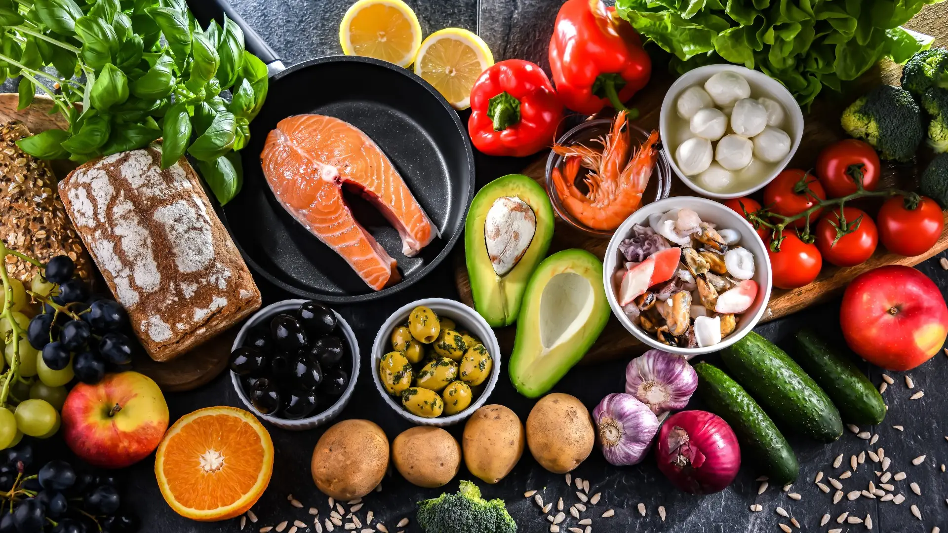 An assortment of anti-inflammatory diet foods including turmeric root, fresh ginger, raw garlic, berries, and leafy green vegetables.