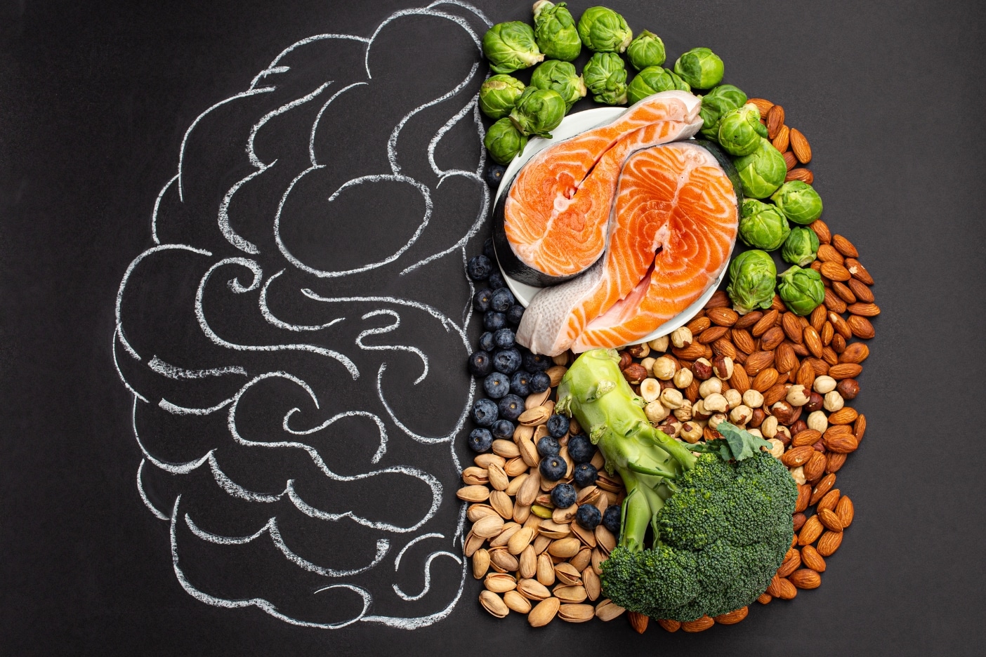 A vibrant arrangement of MIND diet brain foods including organic blueberries, kale, raw walnuts, extra virgin olive oil, and baked salmon.