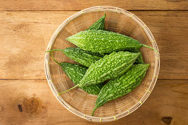 Fresh green bumpy bitter melon pods sliced on a rustic wooden table, highlighting blood sugar-balancing charantin and polypeptide-p.