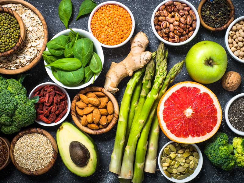A vibrant arrangement of anti-aging longevity staples including dark grapes, aged parmesan, pomegranates, and green tea leaves.